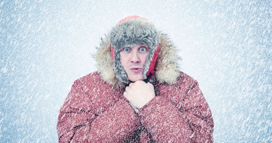 Homme dans un blizzard, gelé dans des vêtements d'hiver se réchauffant les mains. 